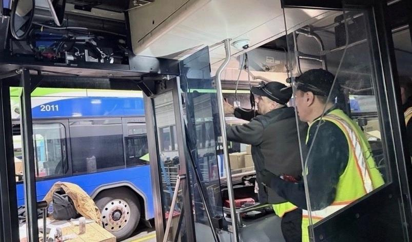 Two technicians working on equipment inside a transit bus.