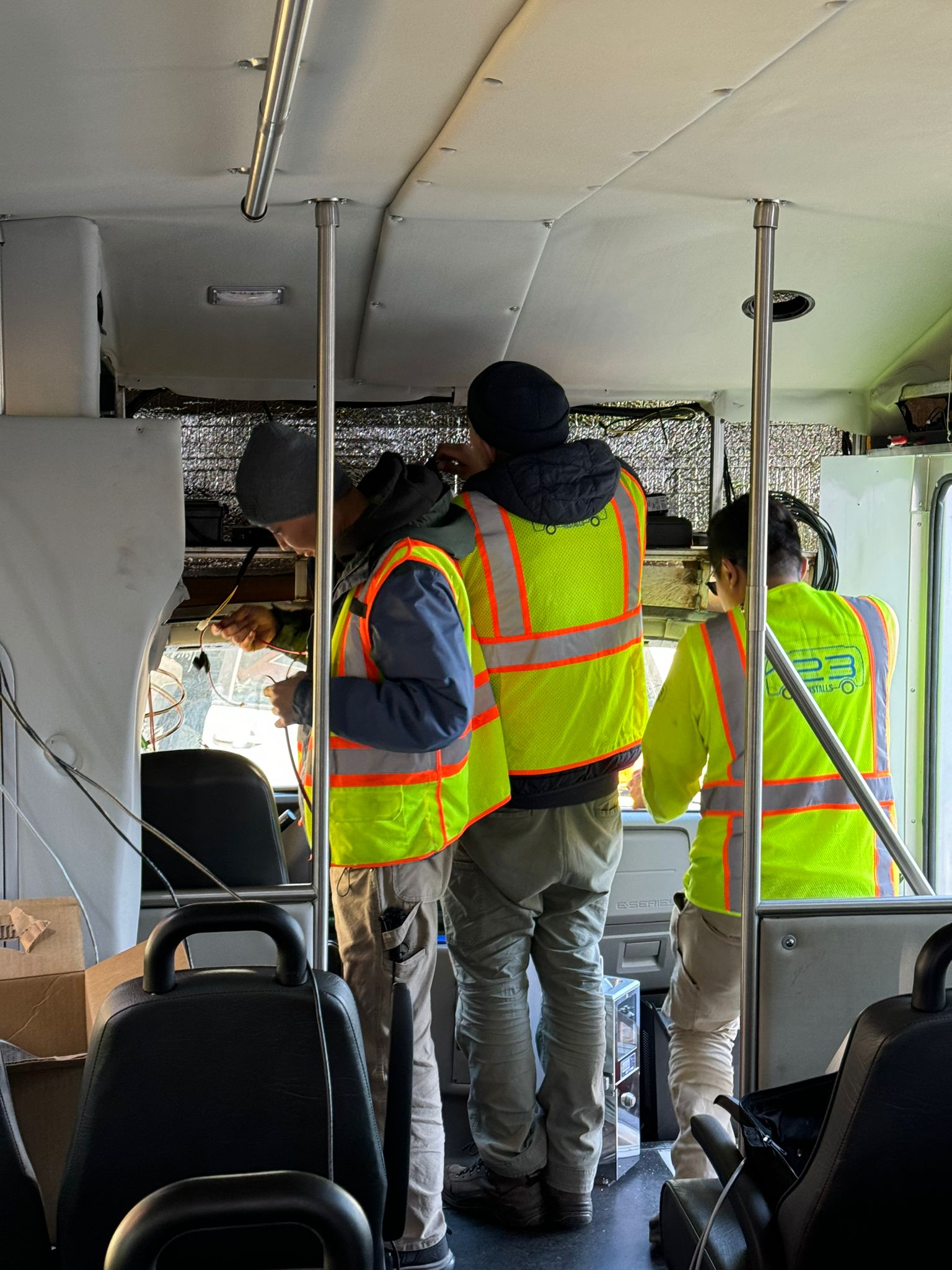 Installation crew working on equipment inside a transit bus.